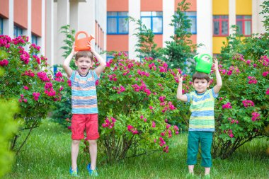 İki küçük gül bahçesinde olan sulama çocuklar çocuk. Aile, g