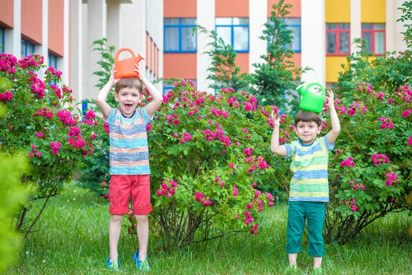 İki küçük gül bahçesinde olan sulama çocuklar çocuk. Aile, g