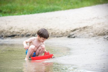 Denizde gemi oyuncakla oynamak bebeğim. Sahilde tatil tatil yaz çocuk os