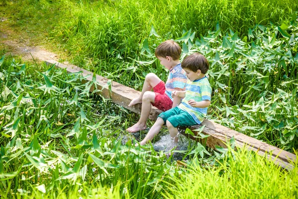 Dos lindos niñitos sentados en un puente de madera — Foto de Stock