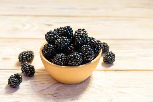 Rustik ahşap arka plan üzerinde beyaz bir seramik kase olgun böğürtlen, kapat