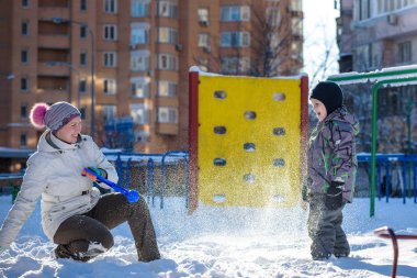 Anne ve oğlu güzel kış günü açık havada, oynamaktan zevk şehirde kar
