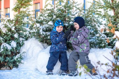 İki küçük çocuklar renkli giysiler açık havada kar yağışı sırasında oynayan çocuk. Kışın soğuk günlerinde çocuklu etkin boş. Mutlu kardeşler ve eğleniyor İkizler kar