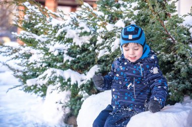Komik küçük çocuk çocuk renkli giysiler açık havada kar yağışı sırasında oynamaya. Kışın soğuk karlı günlerde çocuklu etkin boş. Mutlu çocuk eğlenceli ve kar