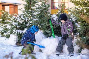 İki küçük çocuklar renkli giysiler açık havada kar yağışı sırasında oynayan çocuk. Kışın soğuk günlerinde çocuklu etkin boş. Mutlu kardeşler ve eğleniyor İkizler kar