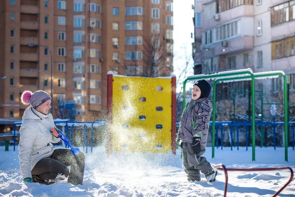 Mother and son enjoying beautiful winter day outdoors, playing with snow in city — Stock Photo, Image