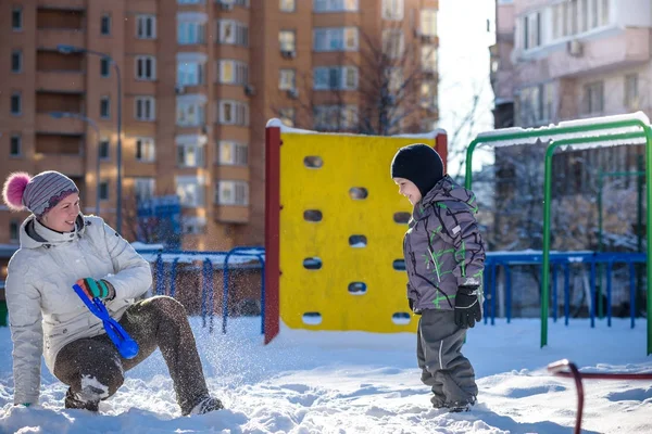 Mother and son enjoying beautiful winter day outdoors, playing with snow in city — Stock Photo, Image