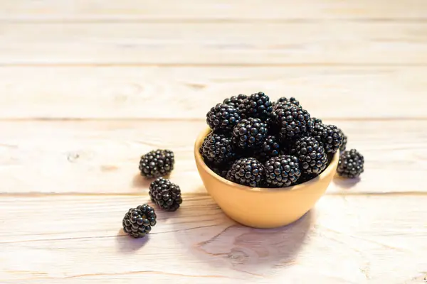 Close up of ripe blackberries in a white ceramic bowl over rustic wooden background — Stock Photo, Image