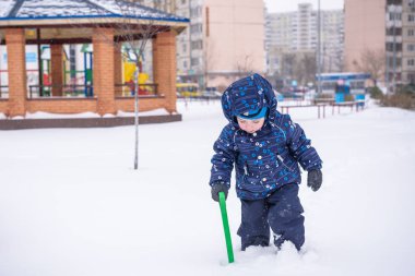 küçük çocuk kar avludan yollarında kürek temizler