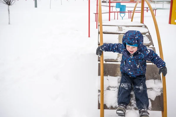 Little boy outdoors in cold winter snow. playground — Stock Photo, Image