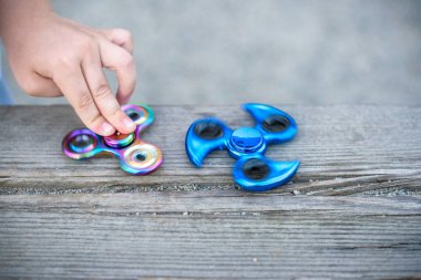 Mavi tutan çocuk ve onun elinde gökkuşağı topluca spinners görüntülemek yukarıdaki her iki becerikli alet iplik