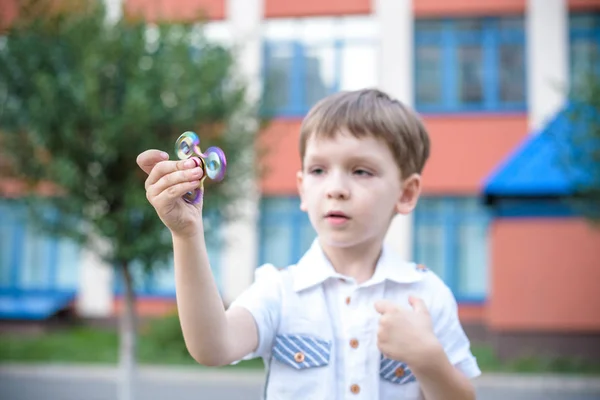 Lindo niño jugando con fidget spinner mano en el día de verano. Juguete popular y de moda para niños y adultos —  Fotos de Stock