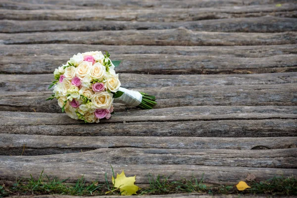 Mooi bruidsboeket liggend op de houten banken — Stockfoto