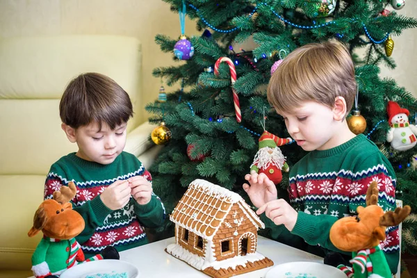 Deux doux garçons, frères, faire la maison de biscuits au pain d'épice, décorer à la maison devant le sapin de Noël, enfant jouant et appréciant, concept de Noël — Photo