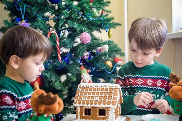 Deux doux garçons, frères, faire la maison de biscuits au pain d'épice, décorer à la maison devant le sapin de Noël, enfant jouant et appréciant, concept de Noël — Photo