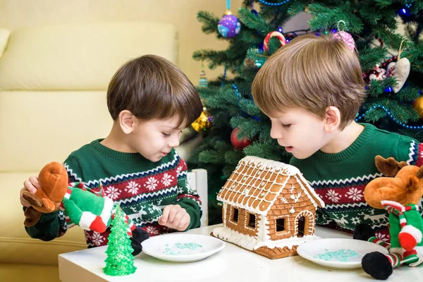 Deux doux garçons, frères, faire la maison de biscuits au pain d'épice, décorer à la maison devant le sapin de Noël, enfant jouant et appréciant, concept de Noël — Photo