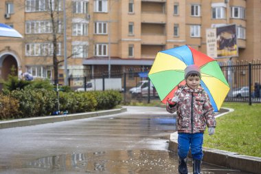 Yağmurlu yaz parkta oynarken küçük çocuk. Çocuk renkli rai ile