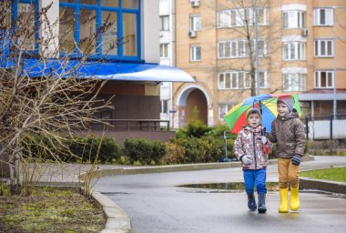İki küçük çocuğu, bir su birikintisi üzerinde bodur küçük şemsiye ile