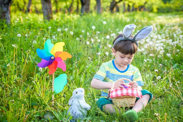 Menino caçando para ovo de Páscoa no jardim da primavera no dia de Páscoa — Fotografia de Stock