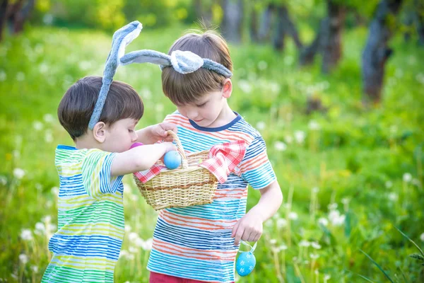 Děti na velikonoční hon na vajíčka v kvetoucí jarní zahradě. Dětské opékání — Stock fotografie
