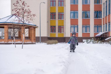 küçük çocuk kar avludan yollarında kürek temizler