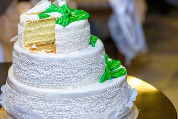 3 poziomowym tort weselny jest ozdobiony kwiatami i stoi na stoliku obok talerz i sztućce — Zdjęcie stockowe