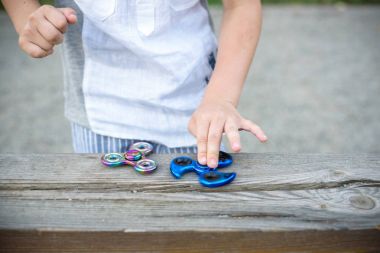 Mavi tutan çocuk ve gökkuşağı spinners onun elinde, görünümü kıpır 