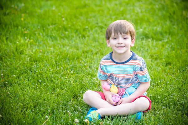 Niño cazando huevos de Pascua en el jardín de primavera el día de Pascua — Foto de Stock