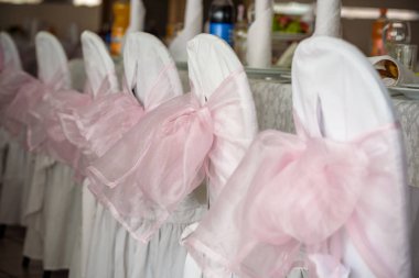 beyaz saten sandalye pembe bir yay ile dekore edilmiş