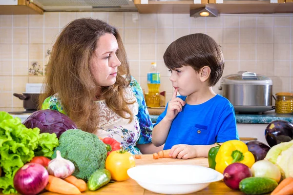 Мати молодої кухарки стоїть зі своїм маленьким сином на кухні і засолюють овочі — стокове фото
