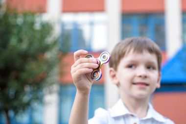 Yaz günü topluca el spinner ile oynayan sevimli küçük çocuk. Yetişkin ve çocuklar için popüler ve modaya uygun oyuncak