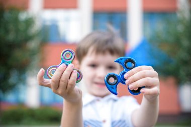 Çocuk iki topluca spinner ile oynarken stres giderici oyuncaklar açık