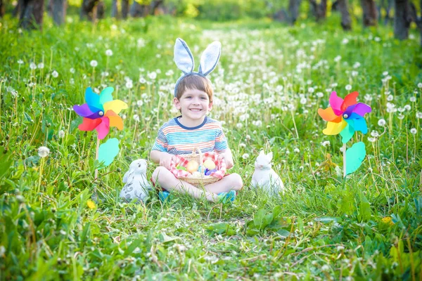 Menino caçando ovo de Páscoa no jardim da primavera no dia de Páscoa. Criança bonito com coelho tradicional comemorando festa — Fotografia de Stock