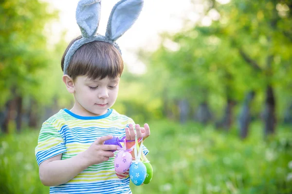 Dzieciak na Easter egg hunt w kwitnące wiosną ogród. chłopiec, szukając kolorowych jaj w łące kwiat — Zdjęcie stockowe