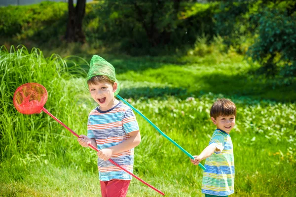 Kepçe-net çayır ile sıcak ve güneşli yaz veya bahar günü oynayan iki küçük kardeş kardeş — Stok fotoğraf