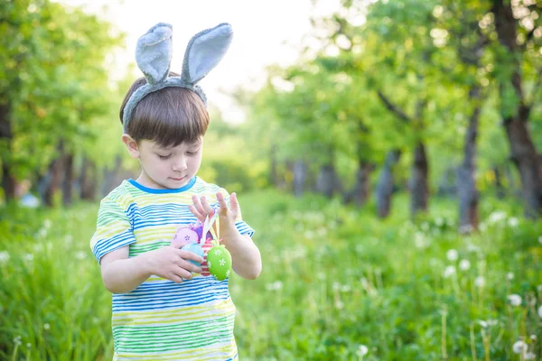 Dzieciak na Easter egg hunt w kwitnące wiosną ogród. chłopiec, wyszukiwanie — Zdjęcie stockowe