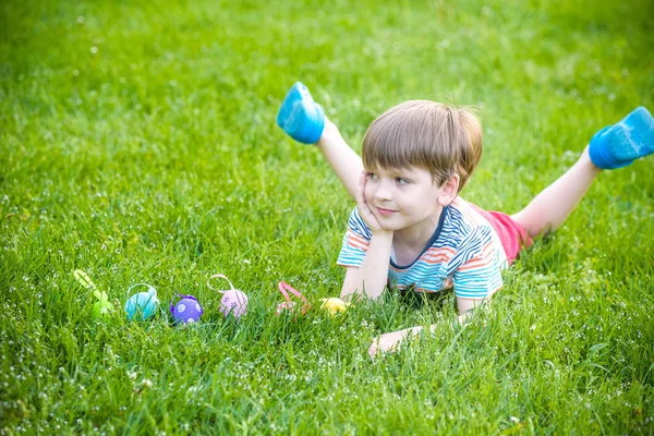 Niño cazando huevos de Pascua en el jardín de primavera el día de Pascua — Foto de Stock