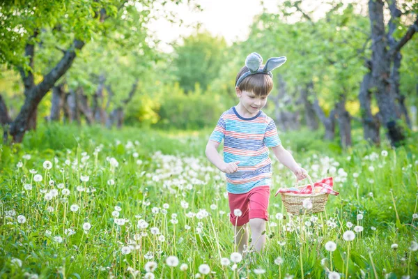 Веселый мальчик держит корзину, полную красочных пасхальных яиц стоять — стоковое фото