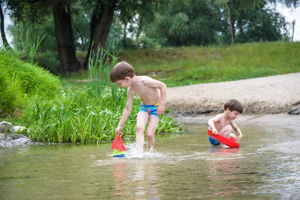 Dos hermanos rubios se divierten en la playa en un día soleado de verano — Foto de Stock