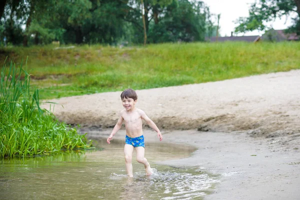 Niño feliz divirtiéndose y corriendo en el agua en el río a la hora del día de verano, estilo de vida veraniego al aire libre, concepto de fin de semana familiar amigable, estilo de vida activo saludable — Foto de Stock