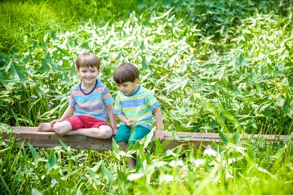 Dos lindos niñitos sentados en un puente de madera — Foto de Stock