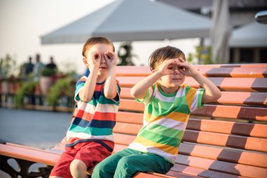 Yeni yürümeye başlayan çocuklar çocuk ve kardeş kardeşi tarafından c bir bankta oturan