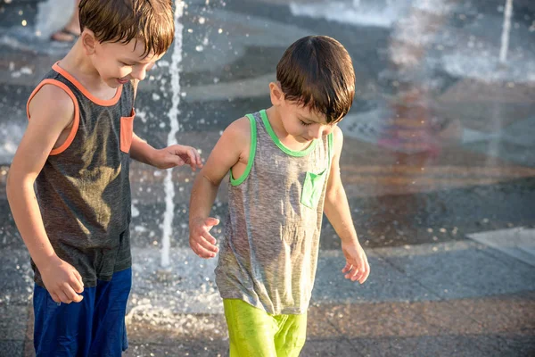 Los niños felices se divierten jugando en la fuente de agua de la ciudad en verano caliente —  Fotos de Stock