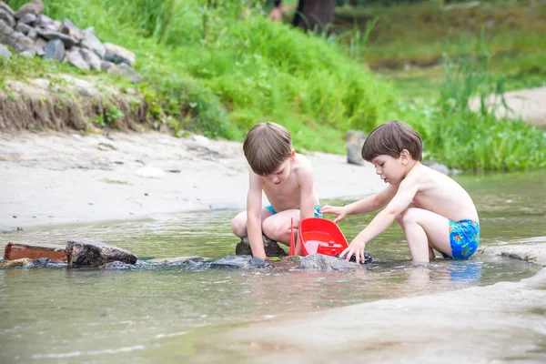 Dos hermanos rubios se divierten en la playa en un día soleado de verano — Foto de Stock