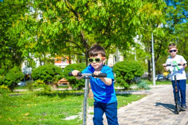 İki küçük çocuk çocuklar itme scooter sürme.