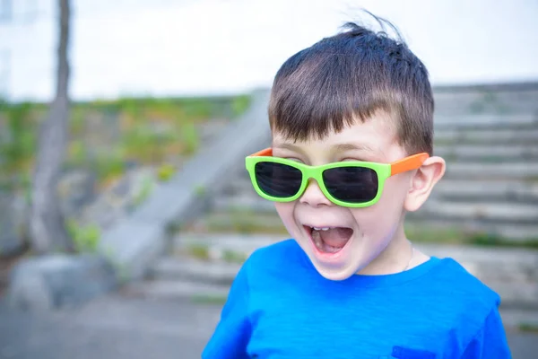 Asustado sorprendido sorprendido mezclado niño caucásico masculino con gafas de sol, posa sobre fondo de pared de ladrillo blanco . — Foto de Stock