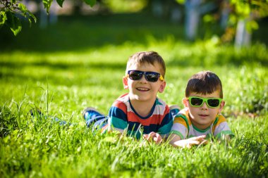 Mutlu gülümseyen erkek kardeş kardeşi çimenlerin üzerinde rahatlatıcı. Kopya alanı görünümüyle kapatın.