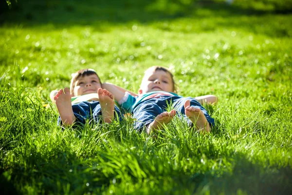 Children laying on grass. Family picnic in spring park — Stock Photo, Image