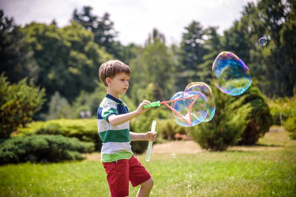 Kleiner Junge spielt mit seinem Seifenblasen-Spielzeug im Park. Kinderaktivität. Frühlingskonzept — Stockfoto
