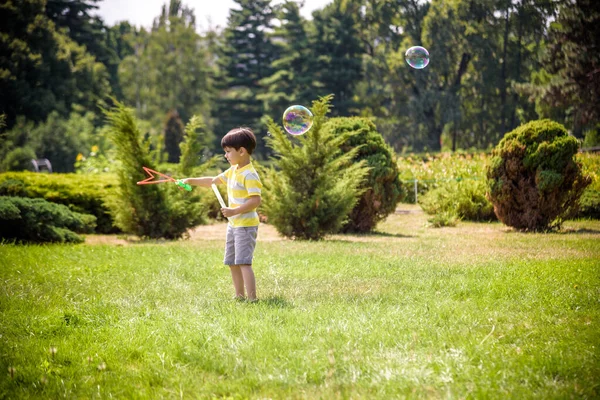 Little boy playing with his soap bubbles toy in the park. Child activity. Springtime concept — Stock Photo, Image